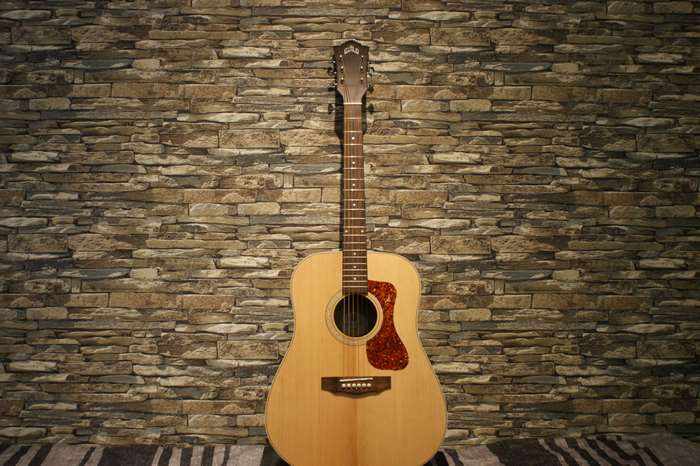 Acoustic guitar against a stone wall