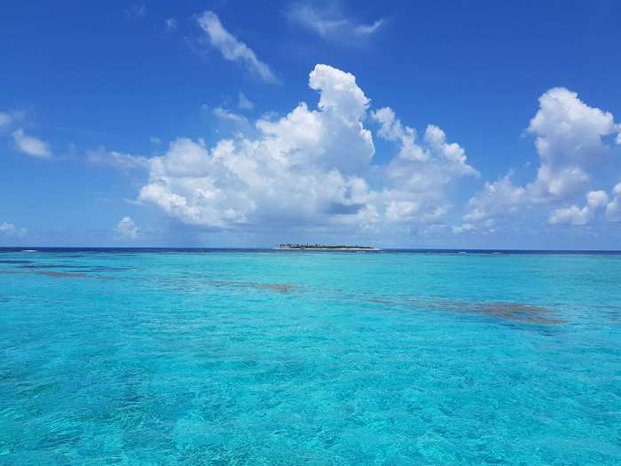 Island in the ocean with blue sky and clouds