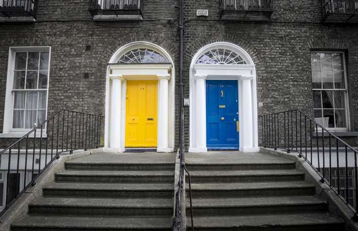 Two colorful doors on a brick building with stairs
