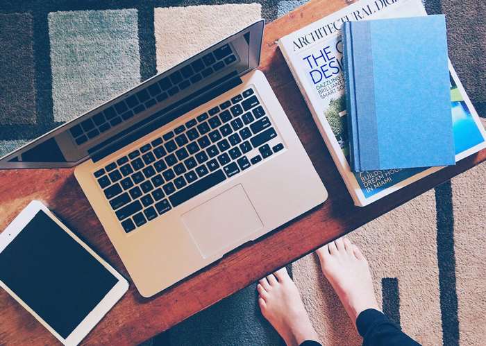 Laptop, tablet, and books on a table with feet