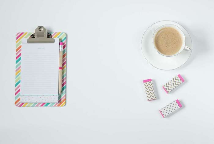 Clipboard with paper, pencil, coffee cup, and erasers