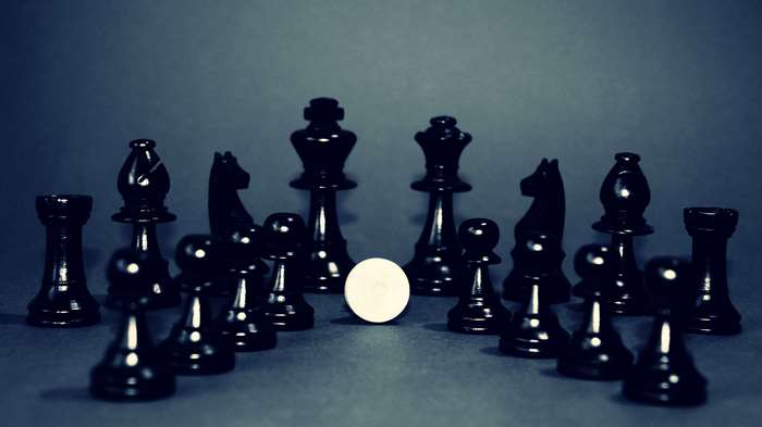 Black and white chess pieces with a white pawn in the center
