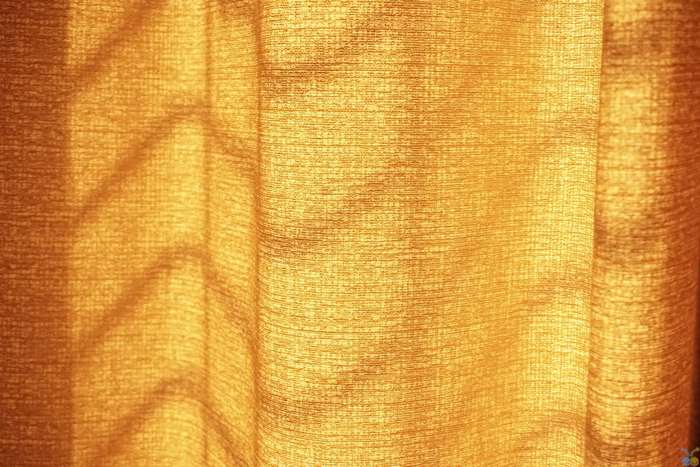 Orange fabric curtain with light and shadow patterns