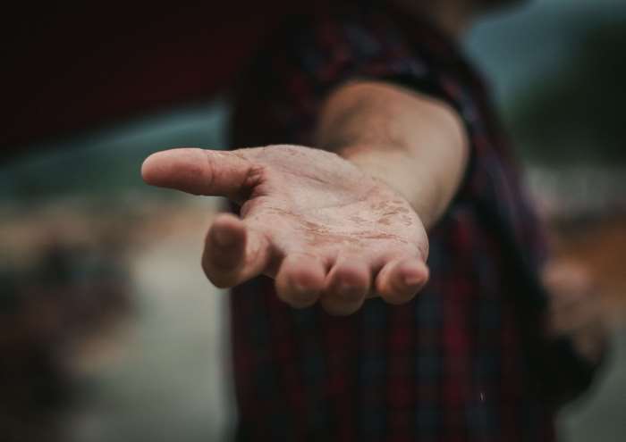 Person offering open palm with dirt