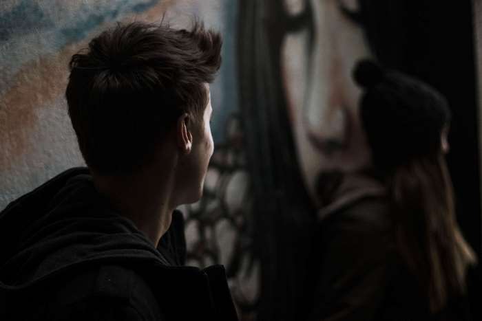 Young man looking at graffiti art of a woman