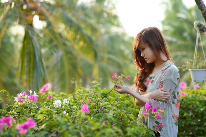 Young woman in a floral shirt holding flowers in a garden