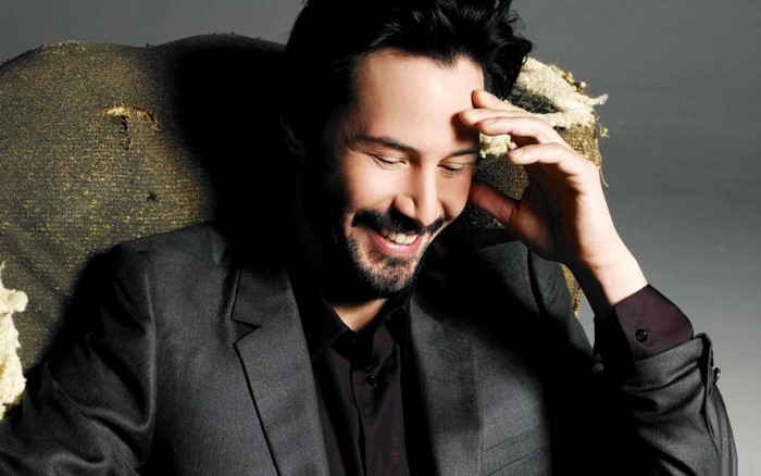 Keanu Reeves smiling in a suit