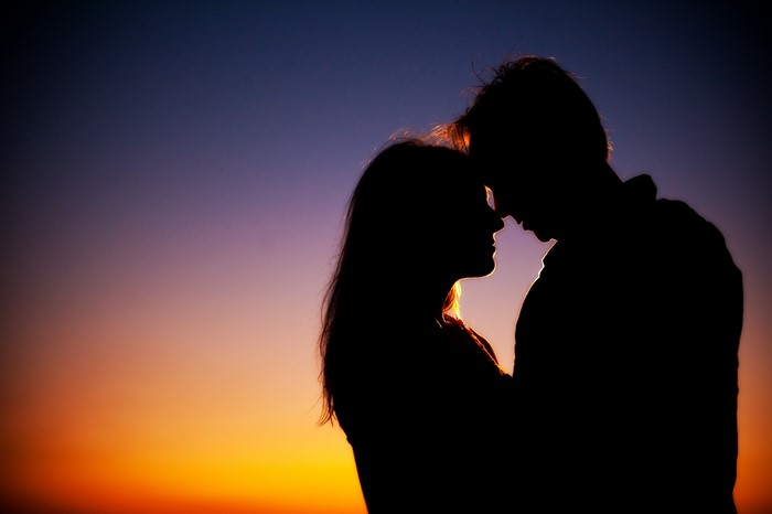 Couple silhouetted against a sunset sky