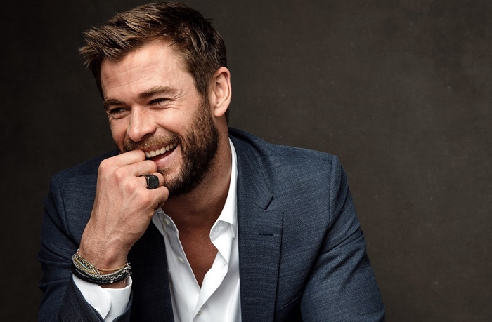 Chris Hemsworth wearing a suit and smiling