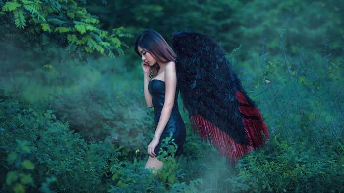 Sad Asian Woman with Black Angel Wings in Forest