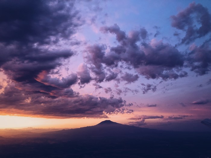 Silhouette of a mountain against a dramatic sunset sky
