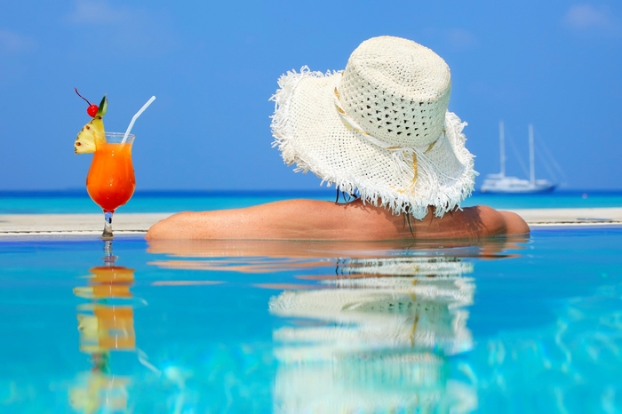 Woman in hat with cocktail in pool