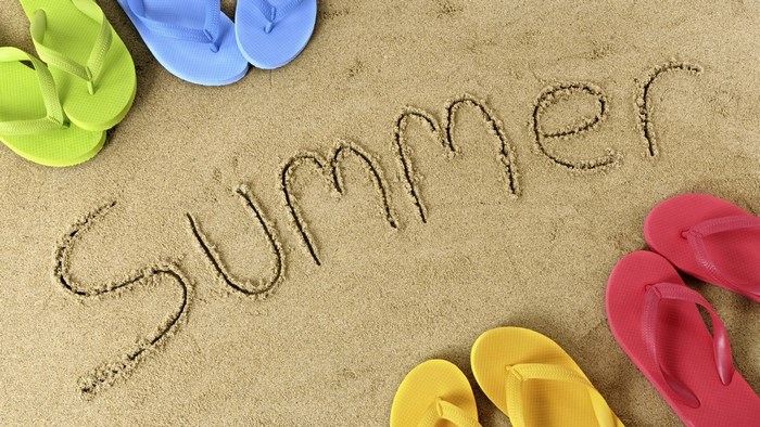 Summer written in sand with flip-flops