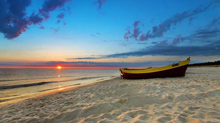 Boat on a sandy beach at sunset