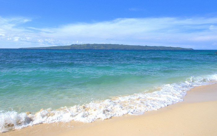 Ocean waves on a sandy beach with a distant island
