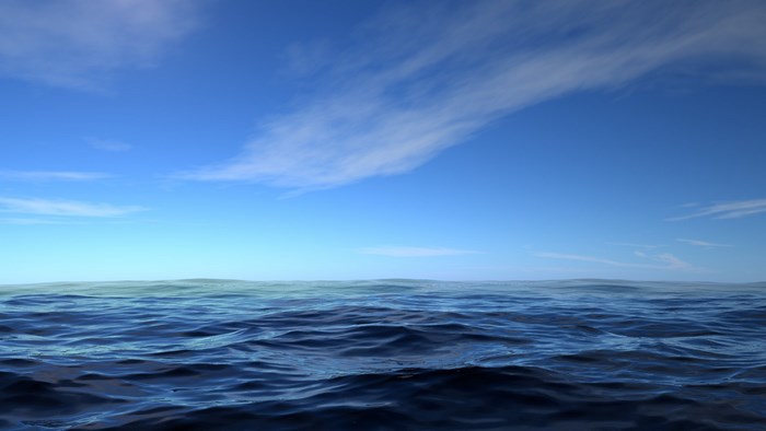 Ocean waves under a blue sky with clouds