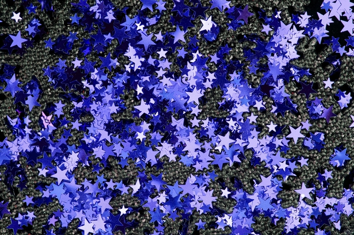 Blue star confetti on a dark textured surface