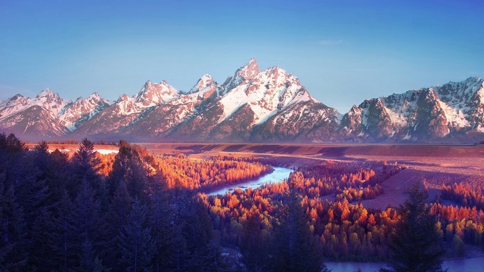 Snow-capped mountains over a forest and river