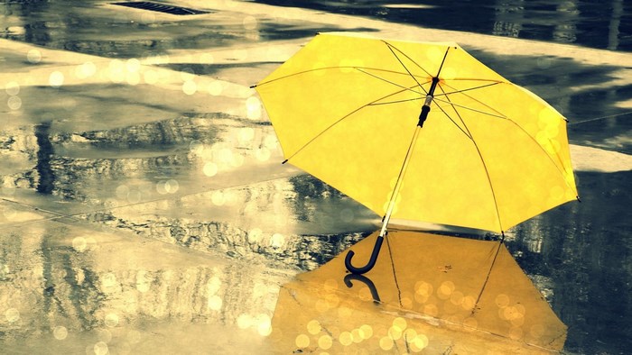 Yellow umbrella on wet pavement