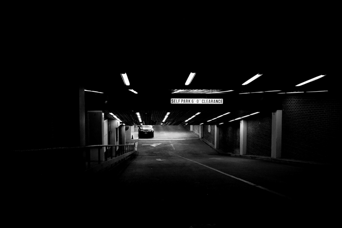 Dark Parking Garage Entrance with Car and Sign