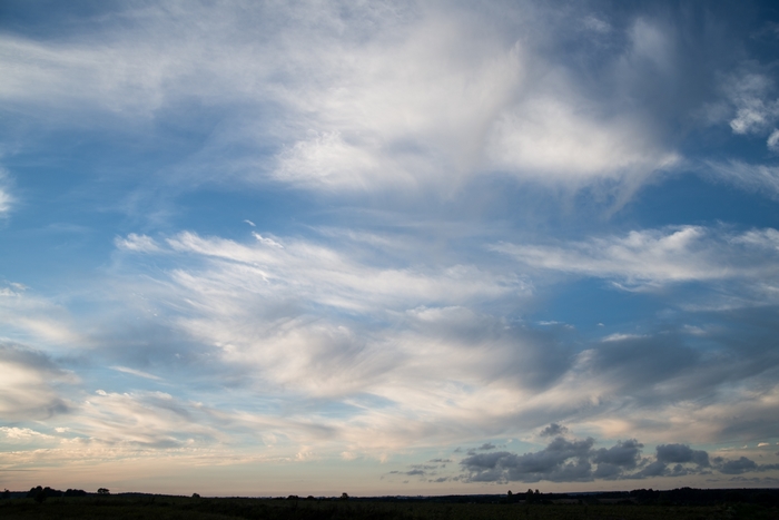 Sky with wispy clouds over a dark horizon