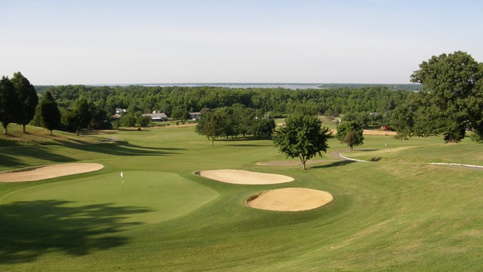 Golf course with bunkers and water in the distance