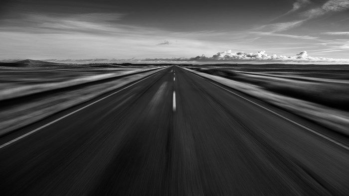 Black and white image of a road with motion blur