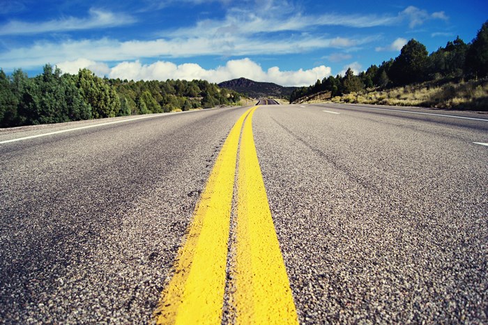 Empty highway with double yellow lines and trees