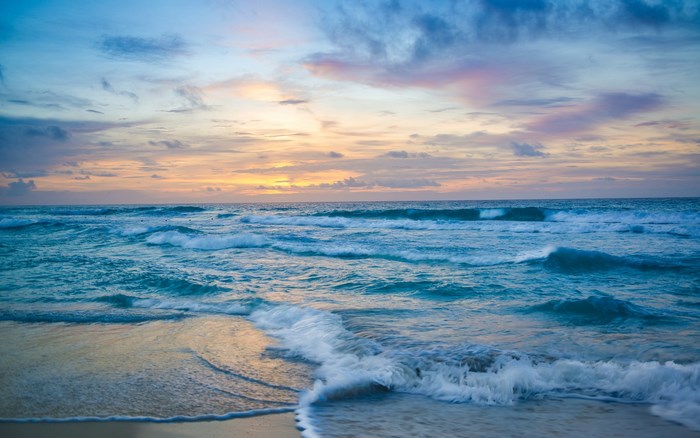 Ocean waves at sunset with colorful clouds
