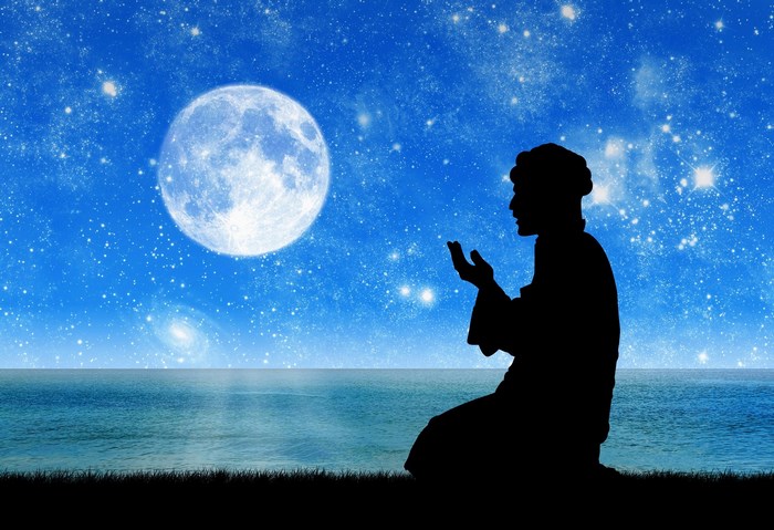 Man praying under the moon and stars