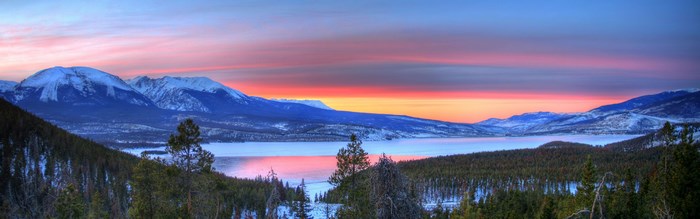 Panoramic winter sunset over a frozen lake and mountains