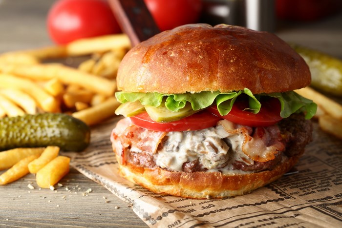 Burger with bacon, lettuce, tomato, pickles, and fries