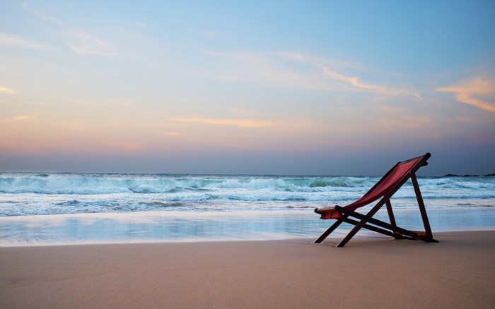 Red beach chair on a sandy beach at sunset