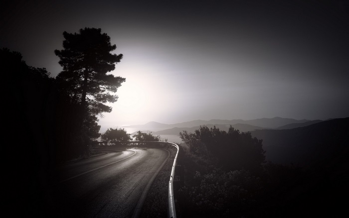 Dark road with trees and mountains