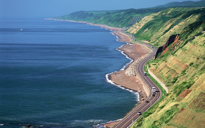 Coastal highway winding along the sea with green hills