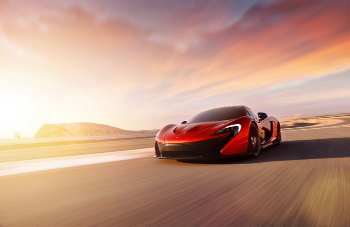 McLaren P1 driving on a road at sunset