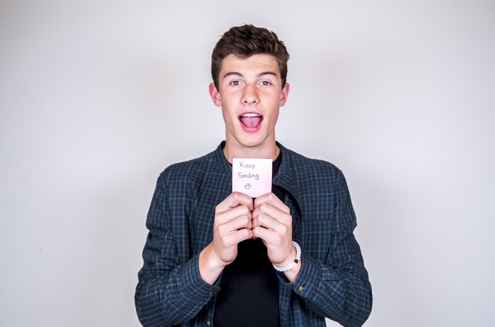 Shawn Mendes holding a 'Keep Smiling' note