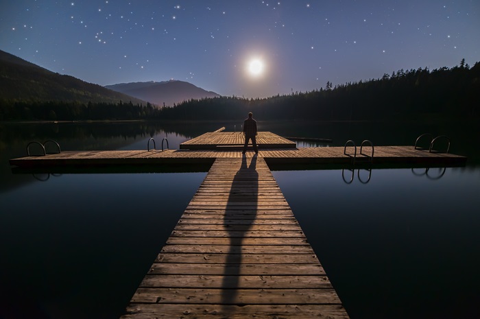 Man on Dock Under Moonlit Starry Sky