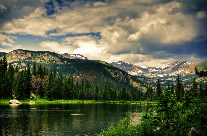 Mountains and lake with pine trees and clouds