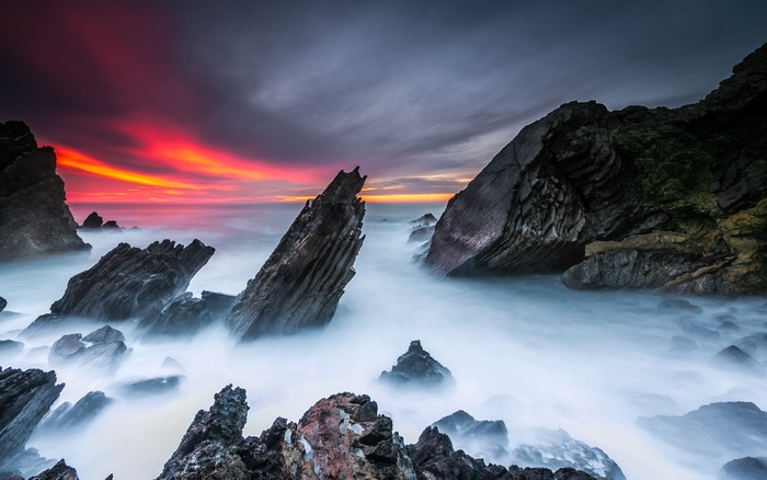 Ocean waves crashing on rocky shore at sunset 4K