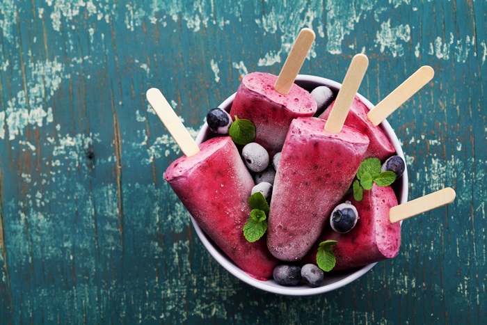 Blueberry popsicles in a bowl with blueberries and mint