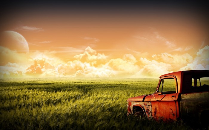 Old red truck in a field with a large moon