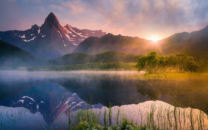 Mountain lake at sunrise with mist and reflections