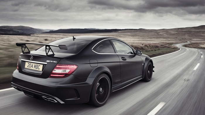 Matte black Mercedes-Benz C63 AMG coupe with spoiler on winding road