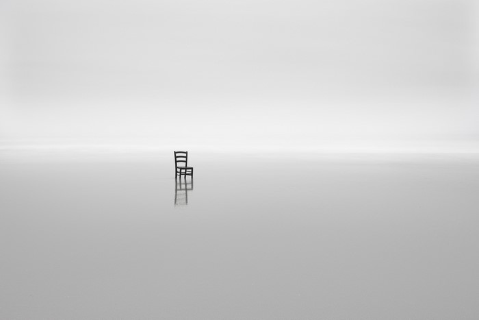 Minimalist monochrome image of a chair on a reflective surface