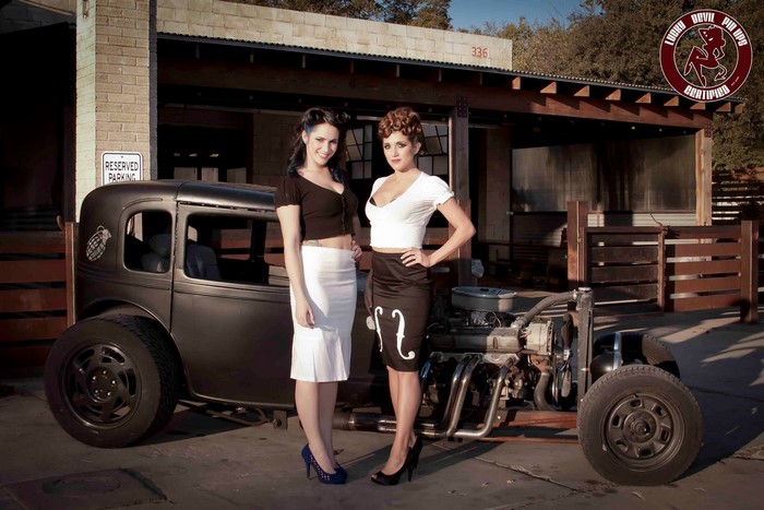 Two women posing with a vintage car