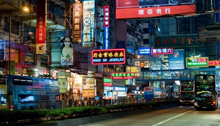 Hong Kong street at night with neon signs and buses