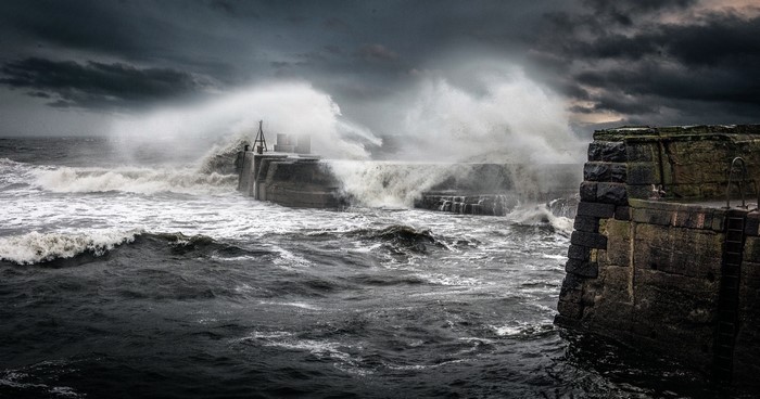 Waves crashing on a stone pier during a storm