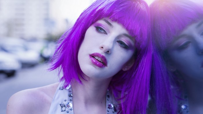 Woman with purple hair and makeup outdoors