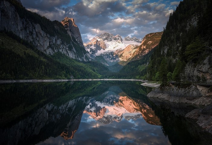 Mountain lake reflection with snow-capped peaks and clouds